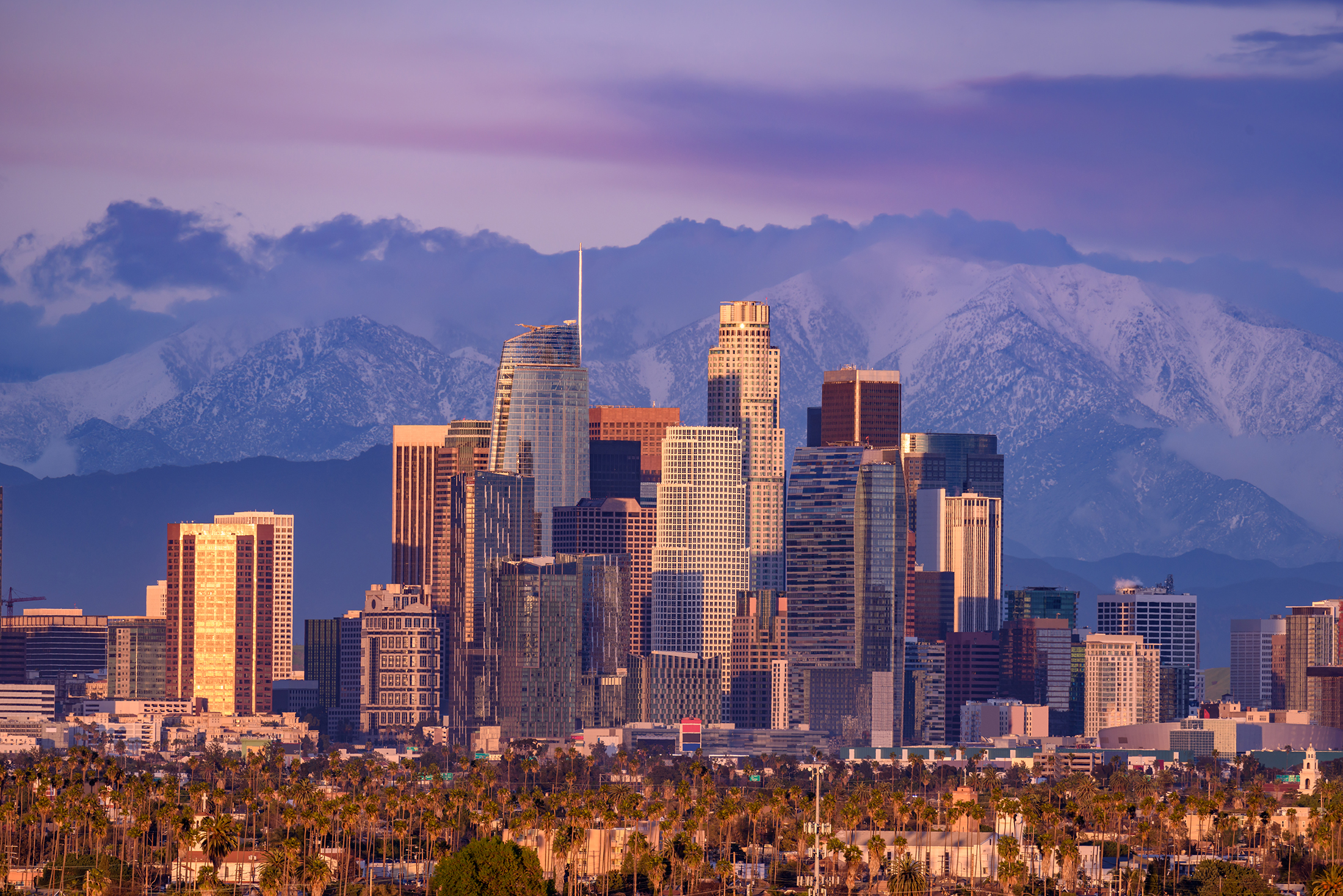 Skyline of Los Angeles against a backdrop of snowcapped mountains.